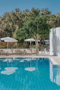 a swimming pool with chairs and umbrellas at Coralli Seaside Resort in Livadakia