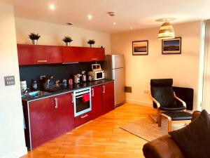 a kitchen with red cabinets and a chair in a room at Cardiff City centre Apartment lifestyle!! in Cardiff