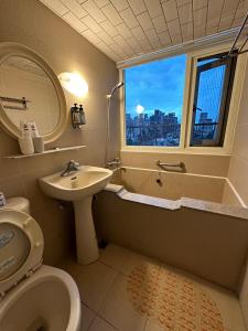 a bathroom with a sink and a toilet and a window at Ming Ren Hotspring Hotel in Jiaoxi