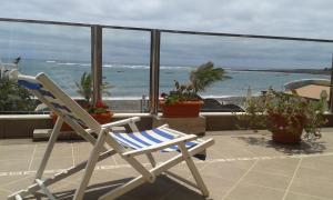 a rocking chair sitting on a balcony overlooking the ocean at Apartamento con encanto en la playa frente al mar "Posada Rent House" in Puerto del Rosario