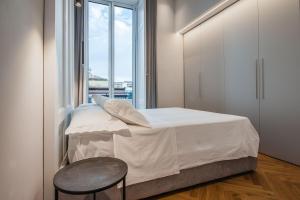 um quarto com uma cama, uma cadeira e uma janela em Ferrini Home - Riso 80 em Catânia