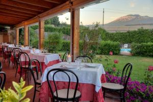 a group of tables and chairs with a mountain in the background at Agriturismo Biologico Corte Aragonese in Santa Maria di Licodia