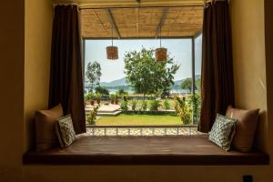 a window seat with a view of a garden at 1br Cottage with Pool - Lakeside Haven by Roamhome in Udaipur