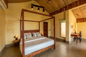 a bedroom with a canopy bed and a desk at 1br Cottage with Pool - Lakeside Haven by Roamhome in Udaipur