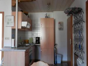 Elle comprend une petite cuisine avec des placards en bois et un réfrigérateur. dans l'établissement Ferienwohnung Heimbeck Kochel, à Kochel am See