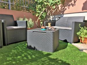 a garden with two wicker chairs and a dog on a table at Bougainvillea Home - Ospedale Policlinico Monserrato in Monserrato +7 photos