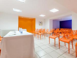 a room with orange chairs and a table with a white table cloth at Hôtel Agena in Lourdes