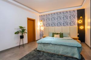 um quarto com uma cama grande e um cobertor azul em Lighthouse Signature Suites em Dakar