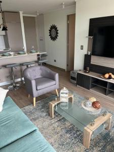 ein Wohnzimmer mit einem Sofa, einem Stuhl und einem TV in der Unterkunft Hermoso Departamento Nuevo en el Corazón de Papudo in Papudo