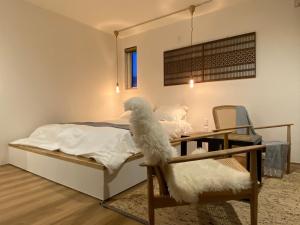 pies siedzący na krześle obok łóżka w obiekcie 縁 EN - The Suites w mieście Furano
