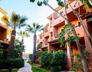 a building with palm trees in front of it at Apartahotel La Espadaña in Rota