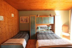 two beds in a room with wooden walls at Acropole Asco in Asco