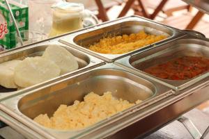a buffet with three trays of food on a table at Pousada Vila do Penedo in Penedo