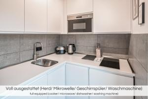 a white kitchen with a sink and a microwave at "Grüne Oase" - Nähe Altstadt - Garage - Ruhig - Nespresso in Dresden
