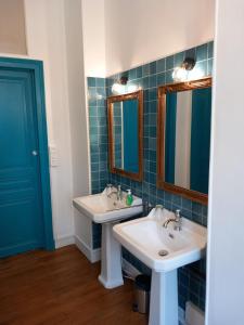 a bathroom with two sinks and two mirrors at Chateau Maleplane in Saint-Léonard-de-Noblat