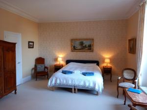 1 dormitorio con 1 cama, 2 sillas y 2 lámparas en Chateau Maleplane, en Saint-Léonard-de-Noblat