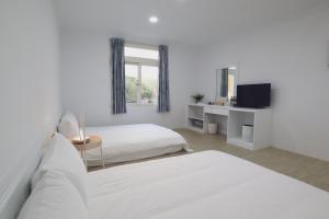 a white bedroom with two beds and a mirror at Party& Dream Homestay in Kenting