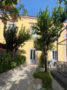 un bâtiment jaune avec des arbres et un banc devant lui dans l'établissement Palazzo Bonaventura 1906, à Ischia