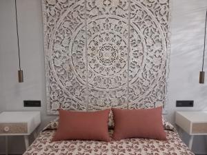 a bed with two pillows in front of a wall at Suite con Jacuzzi de la Haya, junto al Teatro Romano in Merida