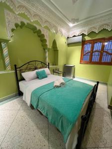 una camera da letto con un grande letto con pareti verdi di Riad Perlamazigh a Zagora