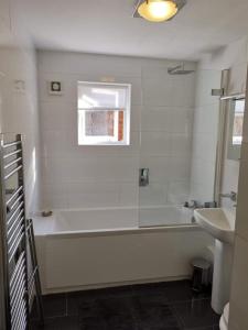Baño blanco con bañera y lavamanos en Flat 4 Summertown Court, en Oxford