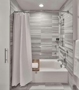 a bathroom with a tub and a shower curtain at Hyatt Centric the Pike Long Beach in Long Beach
