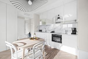a white kitchen with a table and white chairs at GREAT Grano Residence in Gdańsk