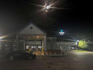 een auto geparkeerd voor een tankstation 's nachts bij Clarion Inn & Suites in Norton Shores