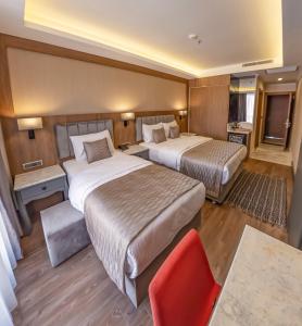 a hotel room with two beds and a red chair at Hamitbey Hotel Yenikapı in Istanbul