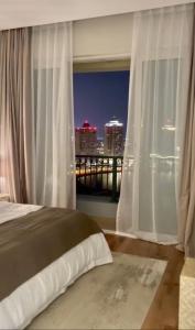 a bedroom with a window with a view of a city at Beachfront Luxury Apartment-The Home-Pearl Island in Doha