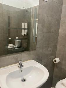 La salle de bains est pourvue d'un lavabo, d'un miroir et de toilettes. dans l'établissement GuestHouse Marquês, à Porto