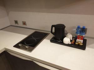a kitchen counter with a stove top and a counter top with bottles of water at Terminal Inn Fully Furnished Hotel & Apartment- Al Mansoura in Doha
