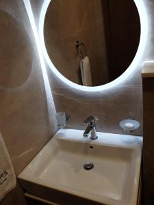 a bathroom sink with a round mirror above it at Terminal Inn Fully Furnished Hotel & Apartment- Al Mansoura in Doha