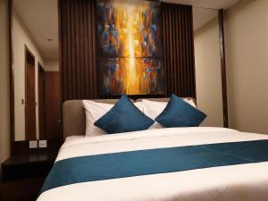 a bedroom with a large bed with blue pillows at Terminal Inn Fully Furnished Hotel & Apartment- Al Mansoura in Doha