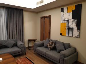 a living room with a couch and a painting on the wall at Terminal Inn Fully Furnished Hotel & Apartment- Al Mansoura in Doha