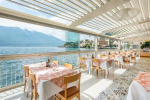 un ristorante con tavoli e sedie e vista sull'acqua di Hotel Le Palme a Limone sul Garda