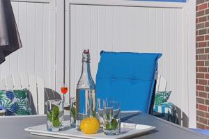 una bottiglia e bicchieri su un tavolo con una sedia blu di SiebenSiel in Greetsiel a Krummhörn