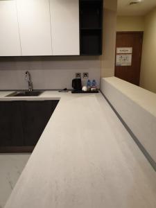 a kitchen with white cabinets and a counter top at Terminal Inn Fully Furnished Hotel & Apartment- Al Mansoura in Doha