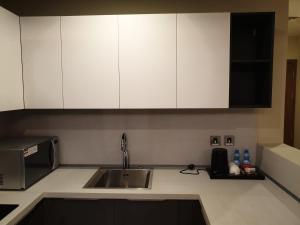 a kitchen counter with a sink and white cabinets at Terminal Inn Fully Furnished Hotel & Apartment- Al Mansoura in Doha