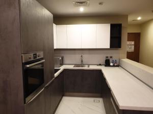 a small kitchen with white cabinets and a sink at Terminal Inn Fully Furnished Hotel & Apartment- Al Mansoura in Doha