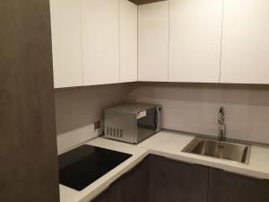 a kitchen with white cabinets and a sink and a microwave at Terminal Inn Fully Furnished Hotel & Apartment- Al Mansoura in Doha