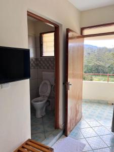 a bathroom with a toilet and a television and a door at Lavender Garden Hotel in Tsavo