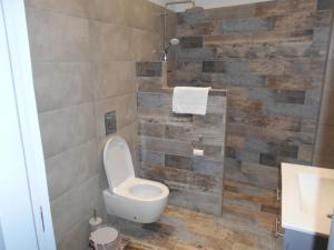 a bathroom with a toilet and a stone wall at SPΛCES PYLOS Apartments in Pylos