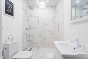 uma casa de banho branca com um chuveiro e um WC. em Ego Apartments Old Town II em Varósvia