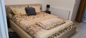 a bed with a flower blanket and pillows on it at Apartament cu 1 camera spatios ,luminos . in Cugir