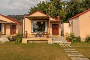 a house with a porch with a bench in the yard at 1br Cottage with Pool - Eagle's Nest by Roamhome in Udaipur