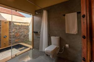 a bathroom with a toilet and a glass shower at 1br Cottage with Pool - Eagle's Nest by Roamhome in Udaipur