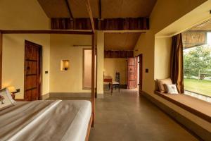 1 dormitorio con cama, escritorio y ventana en 1br Cottage with Pool - Eagle's Nest by Roamhome, en Udaipur