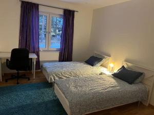 a bedroom with two beds and a window with purple curtains at Beautiful terraced house with private parking in Sandviken