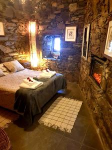 a bedroom with a bed in a stone room with a fireplace at Casa da Carolina in Lousã